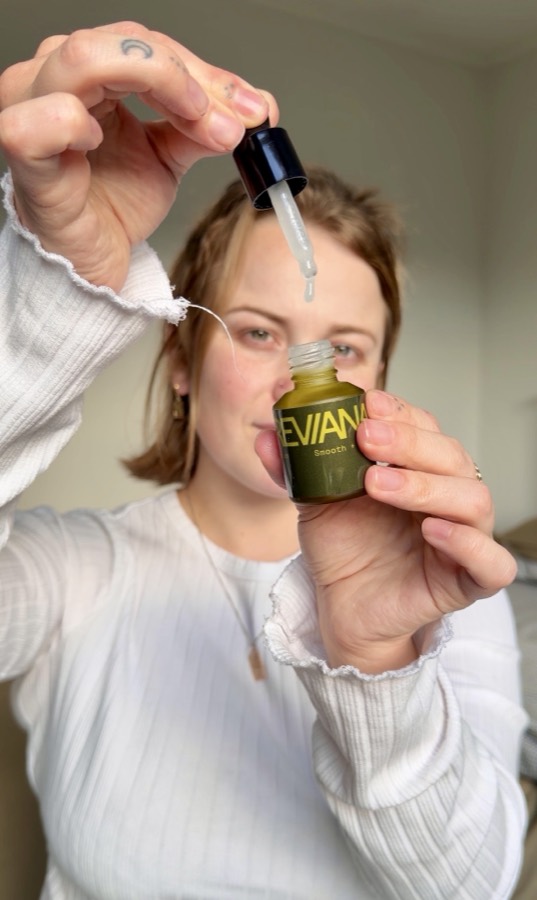 A customer holding the serum dropper above her face