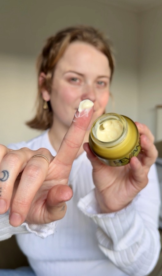 A customer with a fingertip of night cream beside the open jar